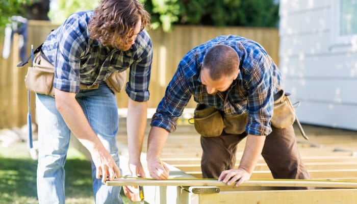 Two Men Measuring Wood Panels For Flooring